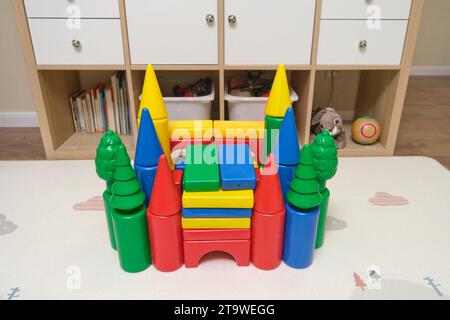 Construction of a children's building from designer cubes on the nursery floor. The castle is built from a multi-colored constructor Stock Photo