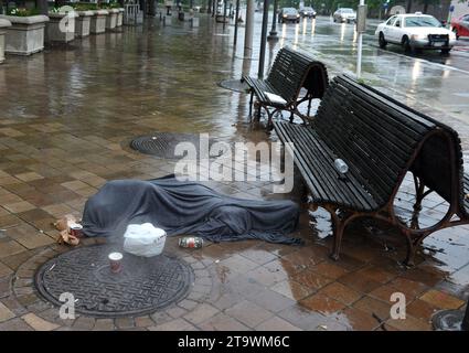 Washington, DC - June 03, 2018: Homeless man lies on the sidewalk on the street in center Washington, DC. Stock Photo