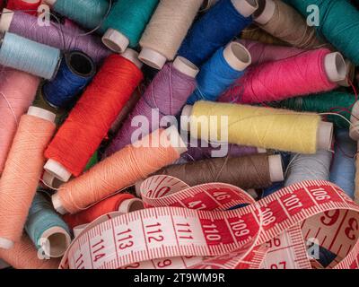 Lots of colorful sewing threads on spools with measuring tape at the bottom Stock Photo