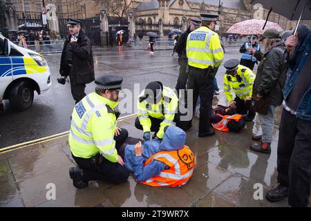 London, UK. 27th Nov, 2023. Just Stop Oil protesters were back protesting in London today. They started their protest at Trafalgar Square, then stopped outside Downing Street. As they tried to sit in the road opposite the House of Commons, they were swiftly arrested and handcuffed by the Met Police. All five protesters were taken away in police vans. The maximum penalty for the wilful obstruction of a highway in England and Wales is 51 weeks in prison. Offenders can also be fined. Credit: Maureen McLean/Alamy Live News Stock Photo