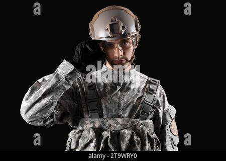 Young male soldier in helmet on black background Stock Photo