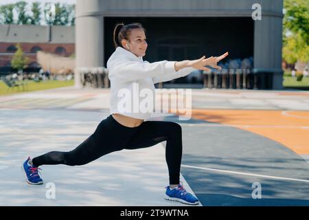 Smiling woman doing lunges outdoors, enjoying a workout in the park Stock Photo