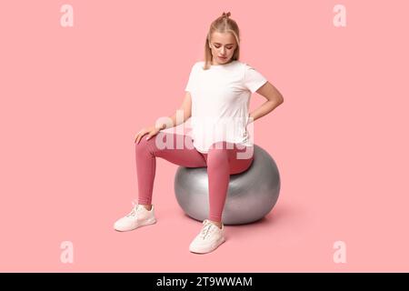 Beautiful young pregnant woman doing exercises with fitball on pink background Stock Photo