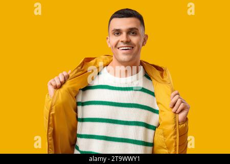 Young man in stylish puffer jacket on yellow background Stock Photo