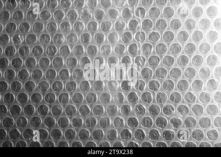 Bubble wrap, close-up background photo. It is a pliable transparent plastic material with bubbles of air used for packing fragile items Stock Photo