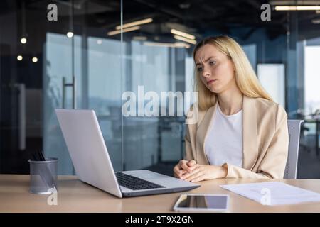 Frustrated sad upset woman working inside office, business woman got bad achievement result, female worker unhappy reading data from laptop screen. Stock Photo