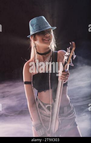 Performer in shimmering stage wear holds her bass, ready to play Stock Photo