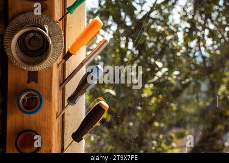 Different types of working screwdrivers and duct tape weigh on the windows in the workshop in daylight, workshop and tools Stock Photo