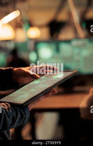 Woman analyzing computer network to hack system on tablet, using code and encrytion to break into security server. Female spy trying to hack database and steal sensitive information. Stock Photo