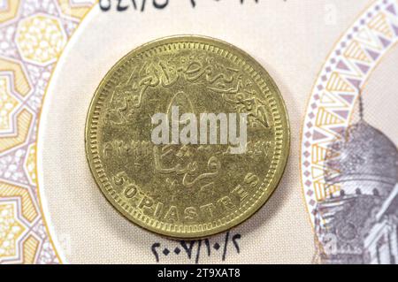 Reverse side date and value of Egyptian 50 piasters coin on Egyptian banknote, with obverse side commemorative coin features eagle head, 90 years of E Stock Photo