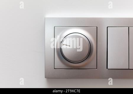 Modern smart rotary knob light dimmer light switch mounted on a wall, front view, frontal shot, object detail closeup. Dimming lights round button, ci Stock Photo