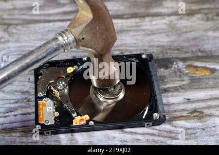 A Hammer on a laptop 2.5 inch hard disk drive storage memory, repair broken computer part, an open hard disc with platters, spindle, actuator and read Stock Photo