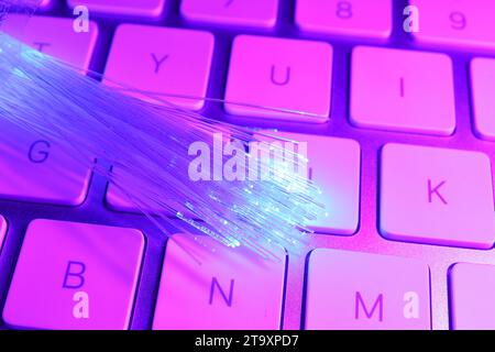 Optical fiber strands transmitting color light on computer keyboard, closeup Stock Photo