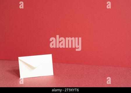 White paper envelope on red table. red wall background Stock Photo