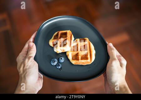 Waffles and blueberries on a dish in men hands Stock Photo