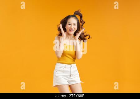 The young adult Asian woman with casual clothes standing on a vivid yellow background Stock Photo