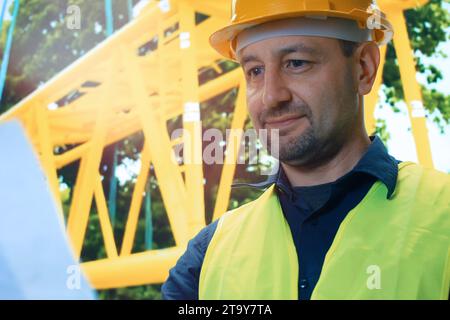 Construction worker at building site smiling at camera. Portrait of mature engineer in a construction site looking at papers . Successful architect we Stock Photo