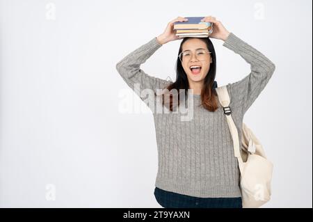 Happy adorable college student with books and backpack on white isolated background. Stock Photo
