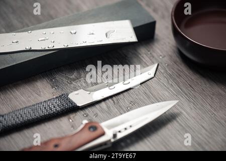 Knife sharpening with whetstone or grindstone. Stock Photo