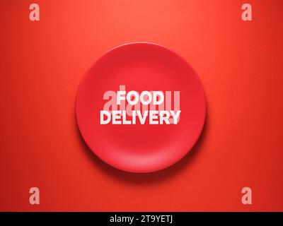 The word Food Delivery on ceramic red plate over red background. Stock Photo