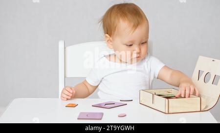 Toddler with blonde hair lays out cut out cards from box Stock Photo