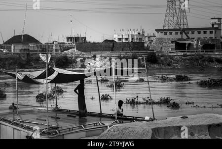 Traditional cargo boat station beside the riverbank. A picturesque scene unfolds along the riverbanks of Bangladesh as traditional cargo boats find th Stock Photo