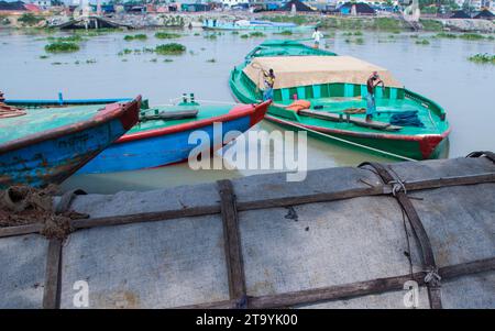 Traditional cargo boat station beside the riverbank. A picturesque scene unfolds along the riverbanks of Bangladesh as traditional cargo boats find th Stock Photo