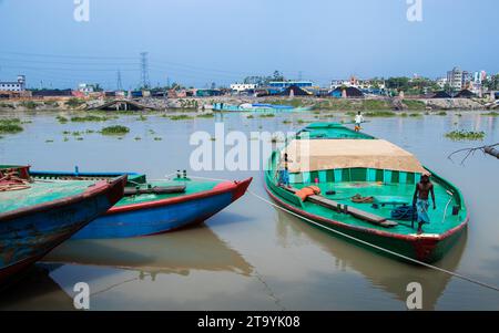 Traditional cargo boat station beside the riverbank. A picturesque scene unfolds along the riverbanks of Bangladesh as traditional cargo boats find th Stock Photo