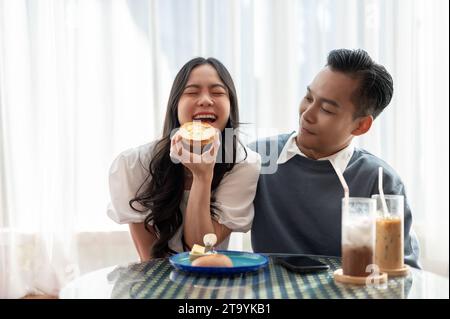 Adorable cute Asian couple having a lovely date at a cafe, having food and drinks. Couple concept Stock Photo