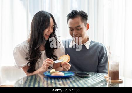 Adorable cute Asian couple having a lovely date at a cafe, having food and drinks. Couple concept Stock Photo