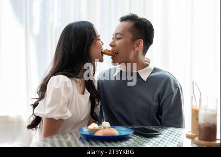 Adorable cute Asian couple having a lovely date at a cafe, having food and drinks. Couple concept Stock Photo