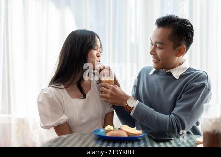 Adorable cute Asian couple having a lovely date at a cafe, having food and drinks. Couple concept Stock Photo