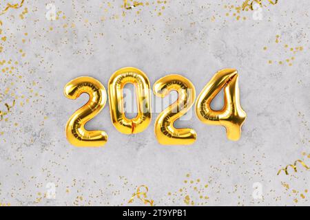 Golden luxury balloons 2023 new year with golden confetti lie on a gray table, top view. Happy New Year 2024 and Marry Christmas card Stock Photo