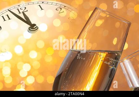 champagne flutes with golden bubbles make cheers on golden light bokeh background with vintage alarm clock is showing midnight, happy new year concept Stock Photo