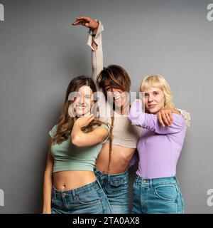 Three happy friends share a close moment, their playful poses expressing the joy and comfort of genuine connection Stock Photo