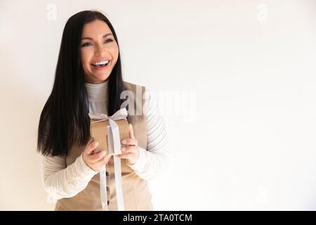 Attractive girl holding a gift in her hands and holding it out to the camera, concept of holiday and gift-giving Stock Photo