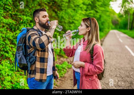 Happy couple hiking in nature and drinking water. Couple enjoying their vacation. Stock Photo