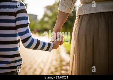 Close up of mother and son holding hands on sunny day. Stock Photo
