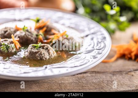 Broth with liver dumplings made from beef liver, bread, eggs and parsley cooked in beef broth. Leberknödelsuppe – German Liver Dumpling Soup. Stock Photo
