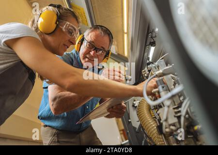 Technicians examining machinery with a clipboard and pen in a workshop Stock Photo