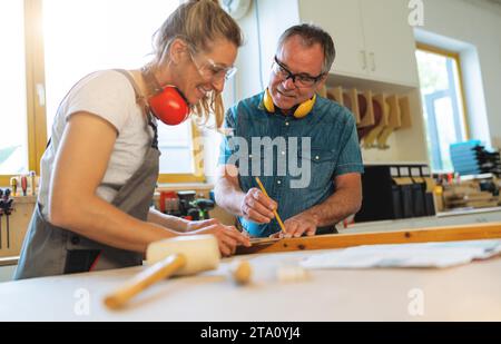 Two carpenters marking measurements on wood in a carpentry workshop Stock Photo