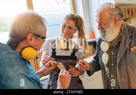 Generations of carpenters in their family business workshop discussing how to use a hand plane Stock Photo