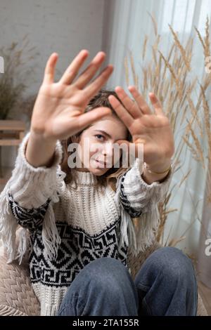 young pretty woman, a teenager girl holds her hands with her palms in front of her face, attracting attention. Focus on the face. Flirting, playful mo Stock Photo