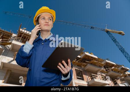 Female engineer with a digital tablet on the background of a building under construction.. Stock Photo