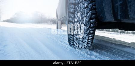 Car is on a snow covered winter road. Close up of winter tire. Stock Photo
