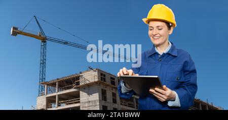 Female engineer with a digital tablet on the background of a building under construction.. Stock Photo