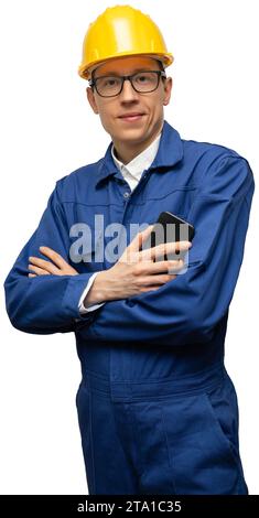 Portrait of a smiling engineer in a glasses, helmet and blue suit looking at camera. Man is holding a smartphone. Isolated... Stock Photo