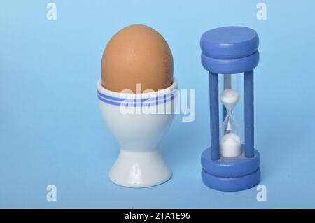Boiled egg and hourglass on a blue background Stock Photo