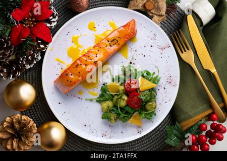 Grilled salmon with orange sauce and a salad. Typical Mediterranean coast dish. Christmas food served on a table decorated with Christmas motifs. Stock Photo