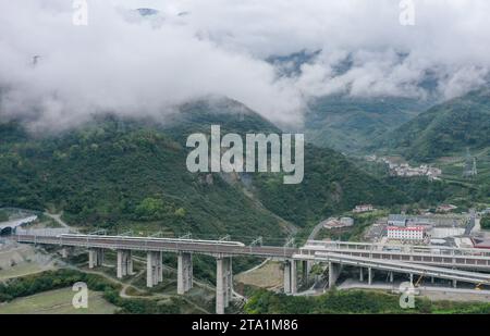 (231128) -- MAOXIAN, Nov. 28, 2023 (Xinhua) -- This aerial photo taken on Oct. 13, 2023 shows a train for commissioning and testing arriving at Maoxian railway station in Maoxian County, southwest China's Sichuan Province. A 238-km section of the Sichuan-Qinghai railway in western China became operational on Tuesday after 12 years of construction. The railway crosses the rugged, earthquake-prone plateau region in northwest Sichuan, and takes a detour to avoid disturbing the Giant Panda National Park. The Sichuan-Qinghai railway will eventually stretch northwestward to Xining, the capita Stock Photo
